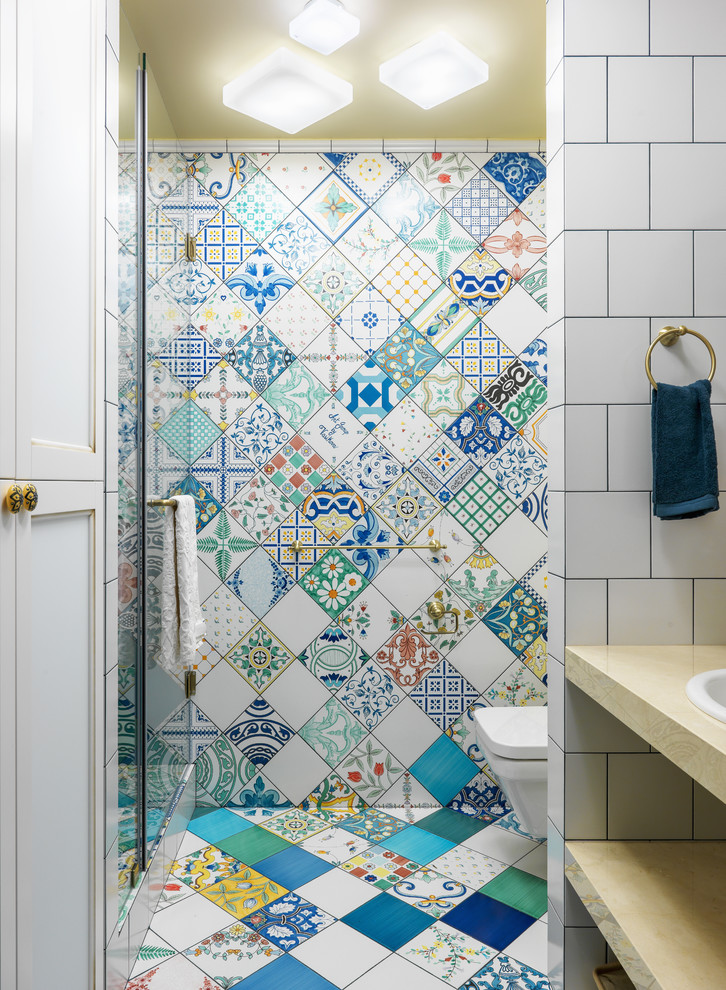 Design ideas for an eclectic 3/4 bathroom in Moscow with open cabinets, an alcove shower, a wall-mount toilet, multi-coloured tile, blue tile, green tile, yellow tile, a drop-in sink, multi-coloured floor, a hinged shower door, ceramic tile, multi-coloured walls and cement tiles.