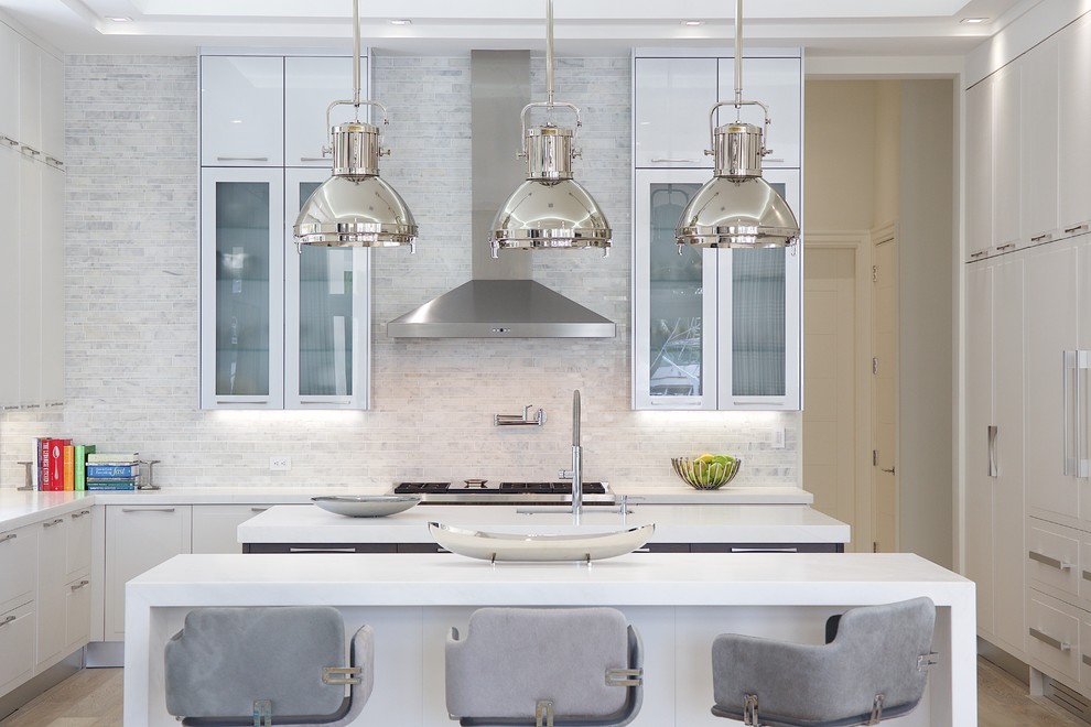 Photo of a large contemporary u-shaped eat-in kitchen in Miami with glass-front cabinets, white cabinets, multiple islands, a single-bowl sink, solid surface benchtops, grey splashback, stone tile splashback, panelled appliances and ceramic floors.