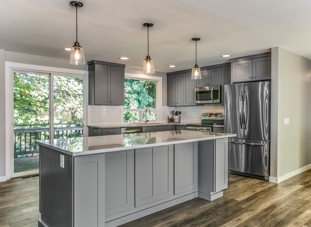 Eat-in kitchen - mid-sized transitional l-shaped dark wood floor and brown floor eat-in kitchen idea with an undermount sink, shaker cabinets, gray cabinets, quartz countertops, white backsplash, subway tile backsplash, stainless steel appliances and an island