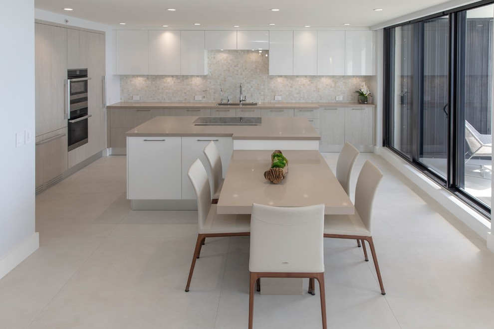 This is an example of a mid-sized contemporary l-shaped open plan kitchen in Other with an undermount sink, flat-panel cabinets, white cabinets, quartz benchtops, beige splashback, marble splashback, panelled appliances, porcelain floors, with island, multi-coloured floor and beige benchtop.