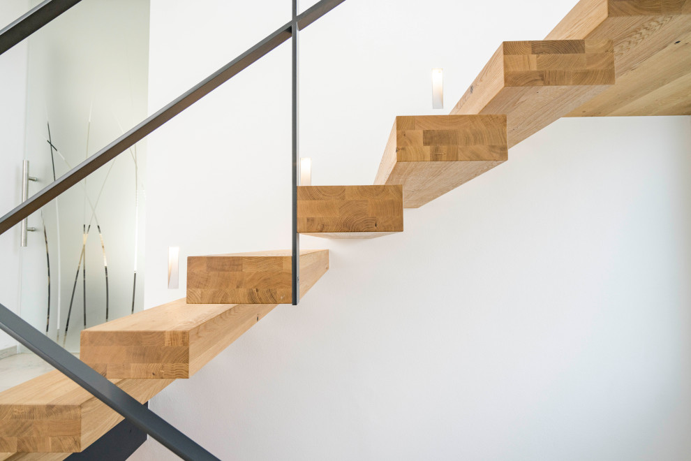 Idée de décoration pour un escalier design avec des marches en bois et un garde-corps en métal.