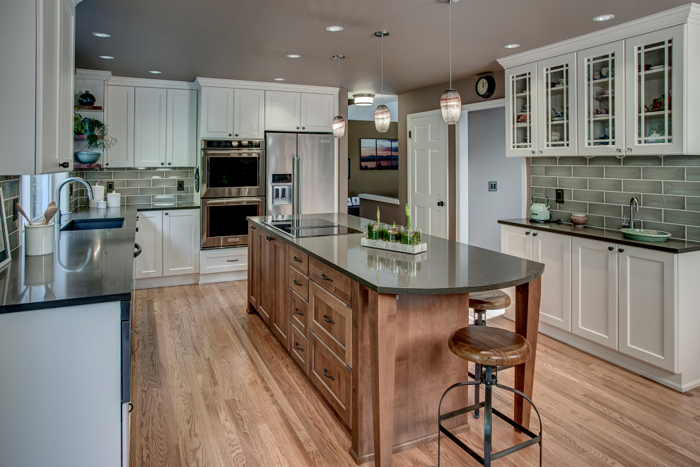 Design ideas for a mid-sized transitional u-shaped kitchen in Seattle with an undermount sink, recessed-panel cabinets, white cabinets, quartz benchtops, ceramic splashback, stainless steel appliances, medium hardwood floors, with island, red floor, grey splashback and grey benchtop.