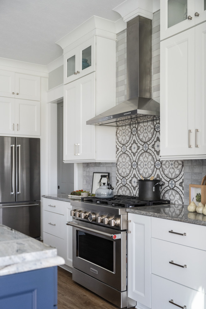 Mid-sized modern galley eat-in kitchen in Indianapolis with an undermount sink, glass-front cabinets, blue cabinets, granite benchtops, white splashback, granite splashback, stainless steel appliances, medium hardwood floors and with island.