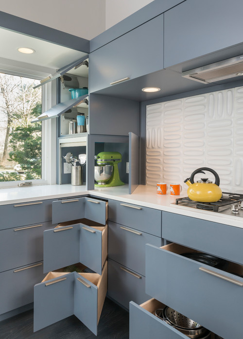 Kitchen cabinet system in matte blue with flat-panel fronts, corner drawers, pull-out storage, and a lift-up appliance garage beside a white 3D backsplash.