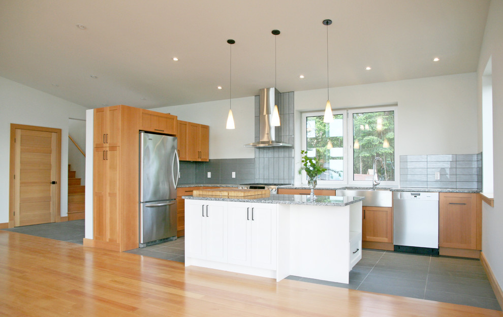Inspiration for a mid-sized contemporary l-shaped eat-in kitchen in Vancouver with a farmhouse sink, shaker cabinets, medium wood cabinets, granite benchtops, grey splashback, glass tile splashback, stainless steel appliances, cement tiles, with island and grey floor.