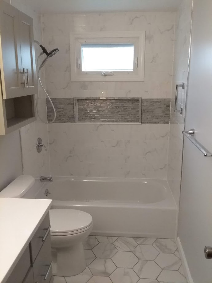 This is an example of a small contemporary master bathroom in New York with recessed-panel cabinets, grey cabinets, an alcove tub, an alcove shower, a two-piece toilet, white tile, ceramic tile, grey walls, porcelain floors, an undermount sink, engineered quartz benchtops, white floor, a shower curtain and grey benchtops.