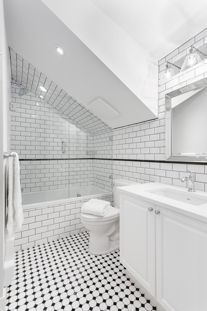 This is an example of a mid-sized traditional 3/4 bathroom in Vancouver with raised-panel cabinets, white cabinets, a drop-in tub, an open shower, white tile, ceramic tile, white walls, an undermount sink, multi-coloured floor, a hinged shower door and a one-piece toilet.