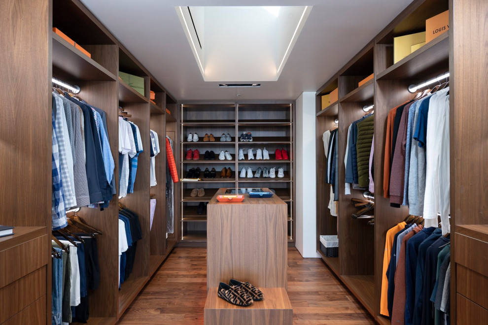 Imagen de vestidor unisex minimalista de tamaño medio con armarios abiertos, puertas de armario de madera oscura, suelo beige y bandeja