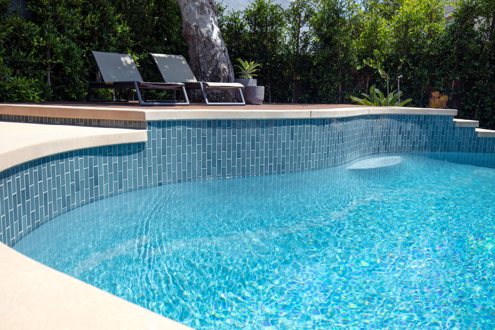 This is an example of a mid-sized midcentury backyard custom-shaped natural pool in Los Angeles with decking.