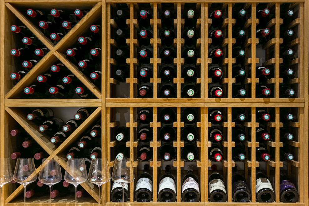 This is an example of an expansive modern wine cellar in London with porcelain floors, storage racks and grey floor.