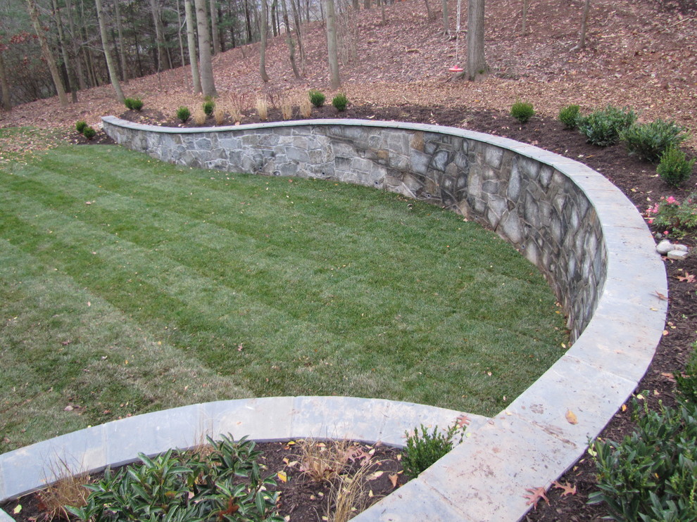 Design ideas for a mid-sized traditional backyard partial sun garden in DC Metro with a retaining wall and natural stone pavers.