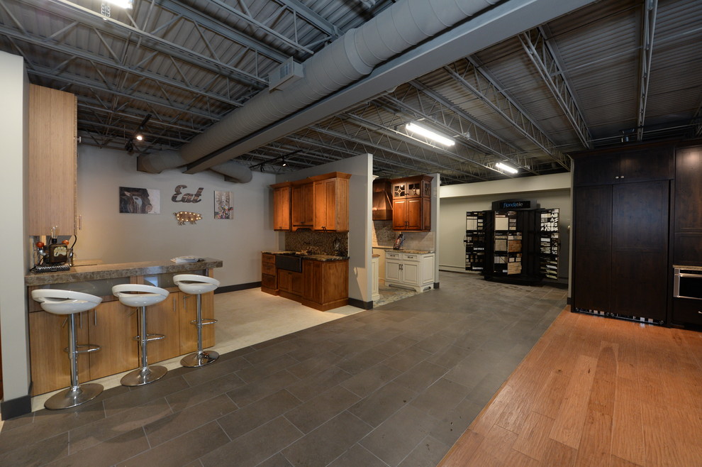 This is an example of a large industrial eat-in kitchen in Cleveland with recessed-panel cabinets, white cabinets, marble benchtops, beige splashback, stainless steel appliances, medium hardwood floors and with island.