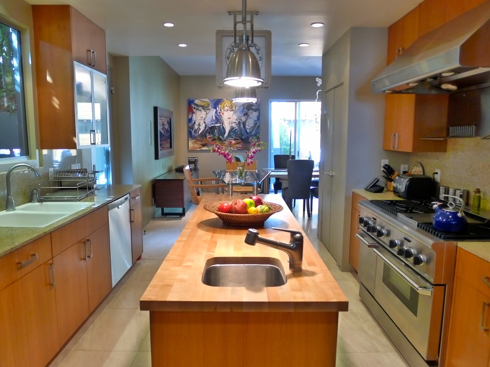 This is an example of a mid-sized contemporary u-shaped eat-in kitchen in Los Angeles with a double-bowl sink, flat-panel cabinets, medium wood cabinets, granite benchtops, beige splashback, stone slab splashback, stainless steel appliances and with island.