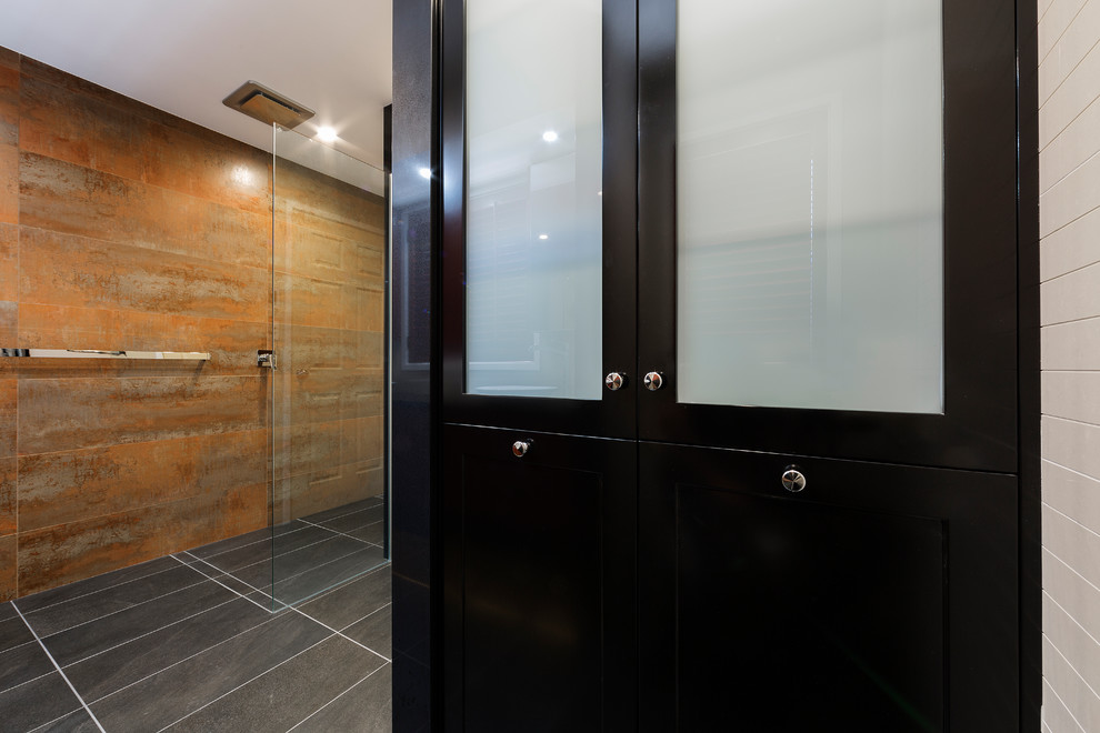 This is an example of a mid-sized contemporary master bathroom in Canberra - Queanbeyan with furniture-like cabinets, medium wood cabinets, a freestanding tub, an open shower, white tile, ceramic tile, white walls, ceramic floors, a vessel sink, granite benchtops, multi-coloured floor, an open shower and black benchtops.