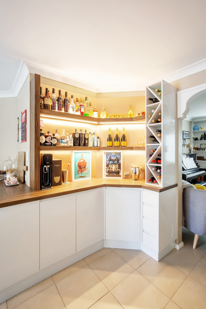 Design ideas for a small contemporary l-shaped home bar in Sydney with flat-panel cabinets, white cabinets, wood benchtops, beige splashback, glass sheet splashback, porcelain floors and beige floor.