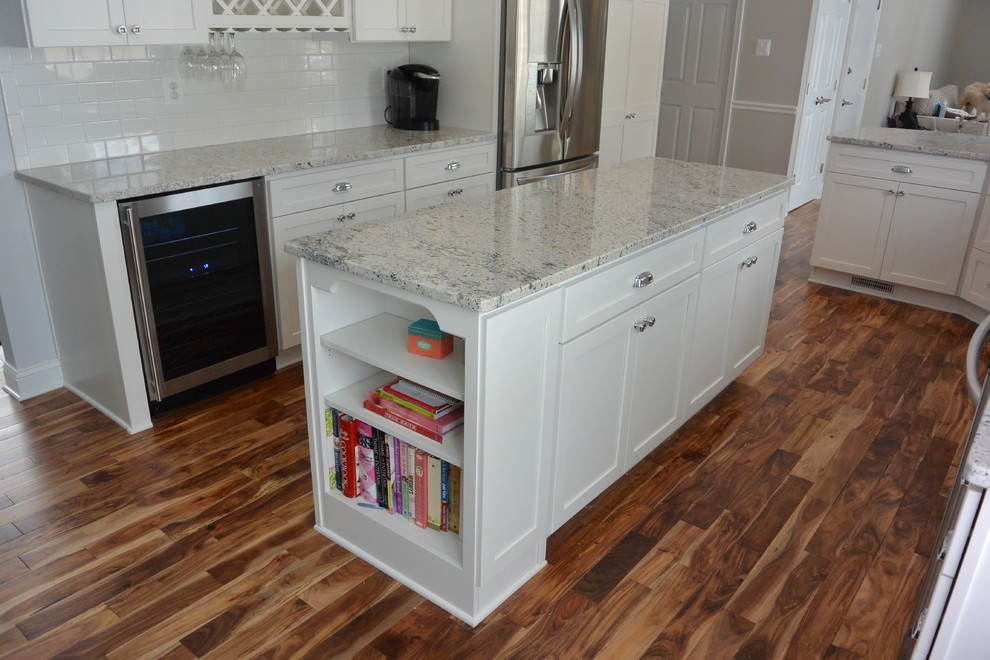 Example of a mid-sized transitional u-shaped medium tone wood floor and brown floor eat-in kitchen design in Baltimore with an undermount sink, recessed-panel cabinets, white cabinets, granite countertops, white backsplash, subway tile backsplash, stainless steel appliances and an island
