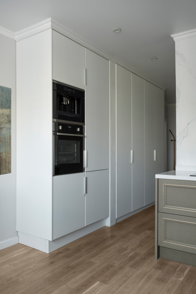 Mid-sized contemporary l-shaped eat-in kitchen in Moscow with an undermount sink, flat-panel cabinets, white cabinets, solid surface benchtops, white splashback, porcelain splashback, stainless steel appliances, medium hardwood floors, no island, beige floor and white benchtop.