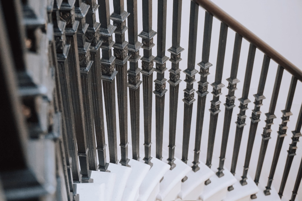 Свежая идея для дизайна: изогнутая лестница в классическом стиле с ступенями из известняка, подступенками из известняка и металлическими перилами - отличное фото интерьера