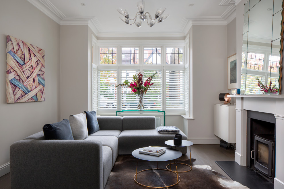 This is an example of a mid-sized transitional living room in London with grey walls, a wood stove and brown floor.