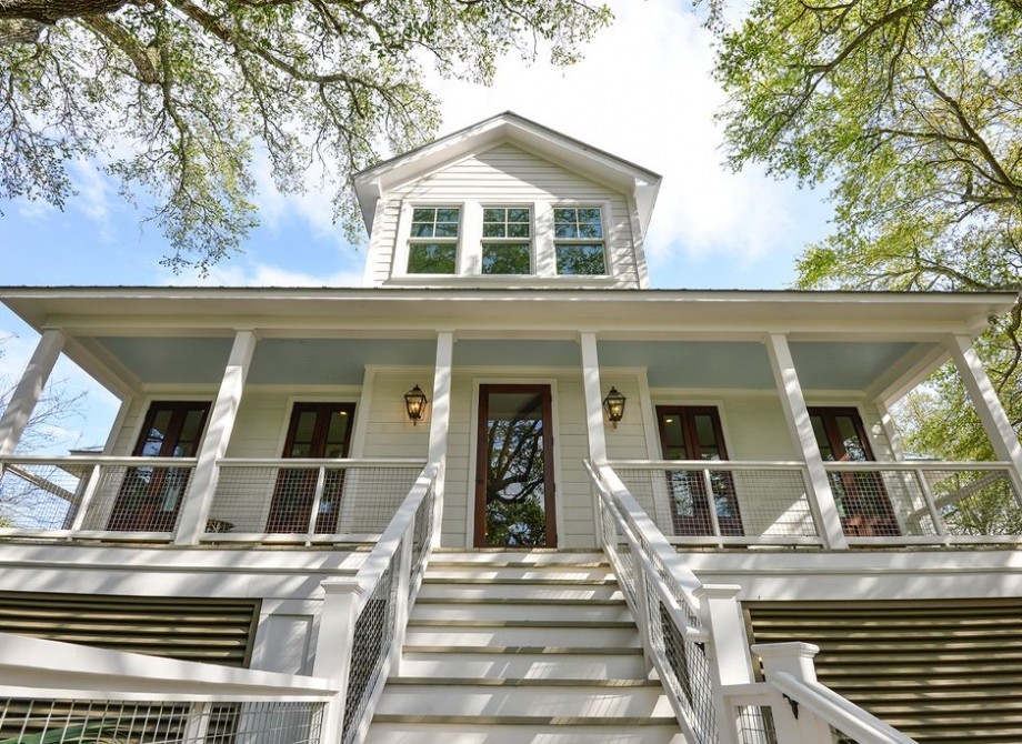 This is an example of a large beach style two-storey white house exterior in Charleston with concrete fiberboard siding, a hip roof and a metal roof.