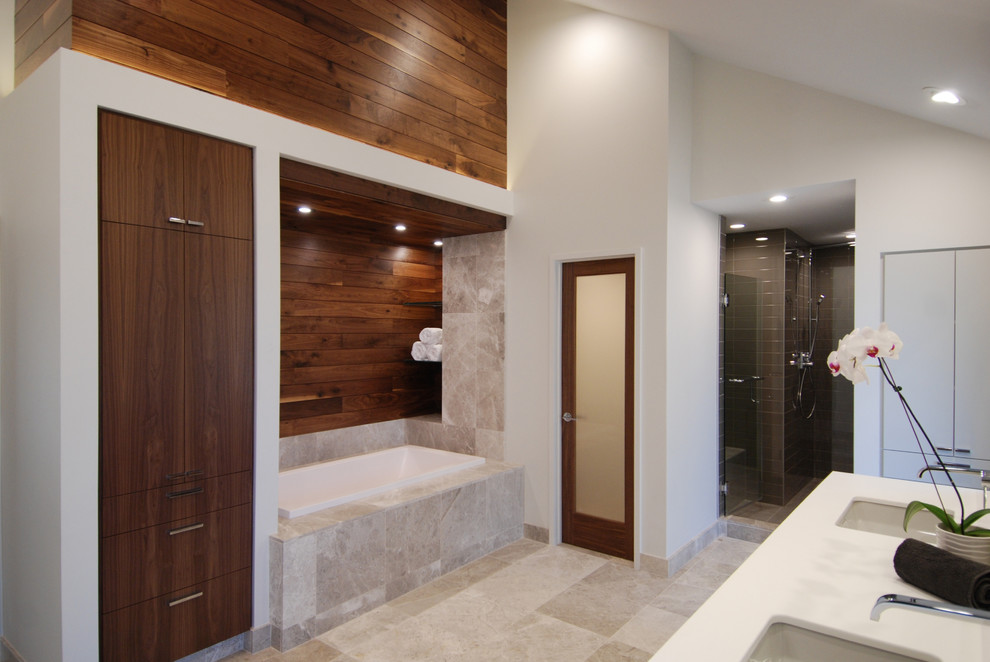 This is an example of a small modern master bathroom in Kansas City with an undermount sink, furniture-like cabinets, dark wood cabinets, solid surface benchtops, a drop-in tub, an open shower, a one-piece toilet, gray tile, stone tile, white walls and limestone floors.