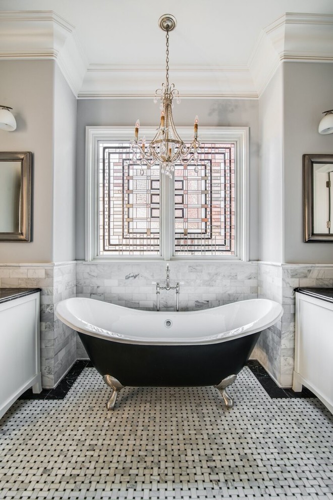 This is an example of a mid-sized traditional master bathroom in Charlotte with white cabinets, a claw-foot tub, black and white tile, white tile, grey walls, mosaic tile floors, a one-piece toilet, a vessel sink, marble benchtops, recessed-panel cabinets and multi-coloured floor.