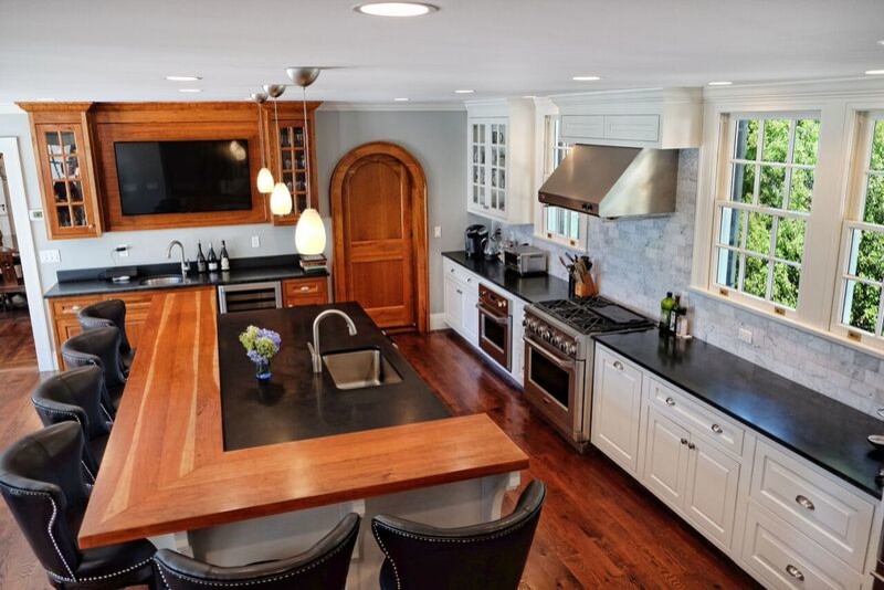 Photo of a mid-sized traditional l-shaped open plan kitchen in Bridgeport with an undermount sink, raised-panel cabinets, white cabinets, wood benchtops, white splashback, marble splashback, stainless steel appliances, dark hardwood floors, with island, brown floor and black benchtop.