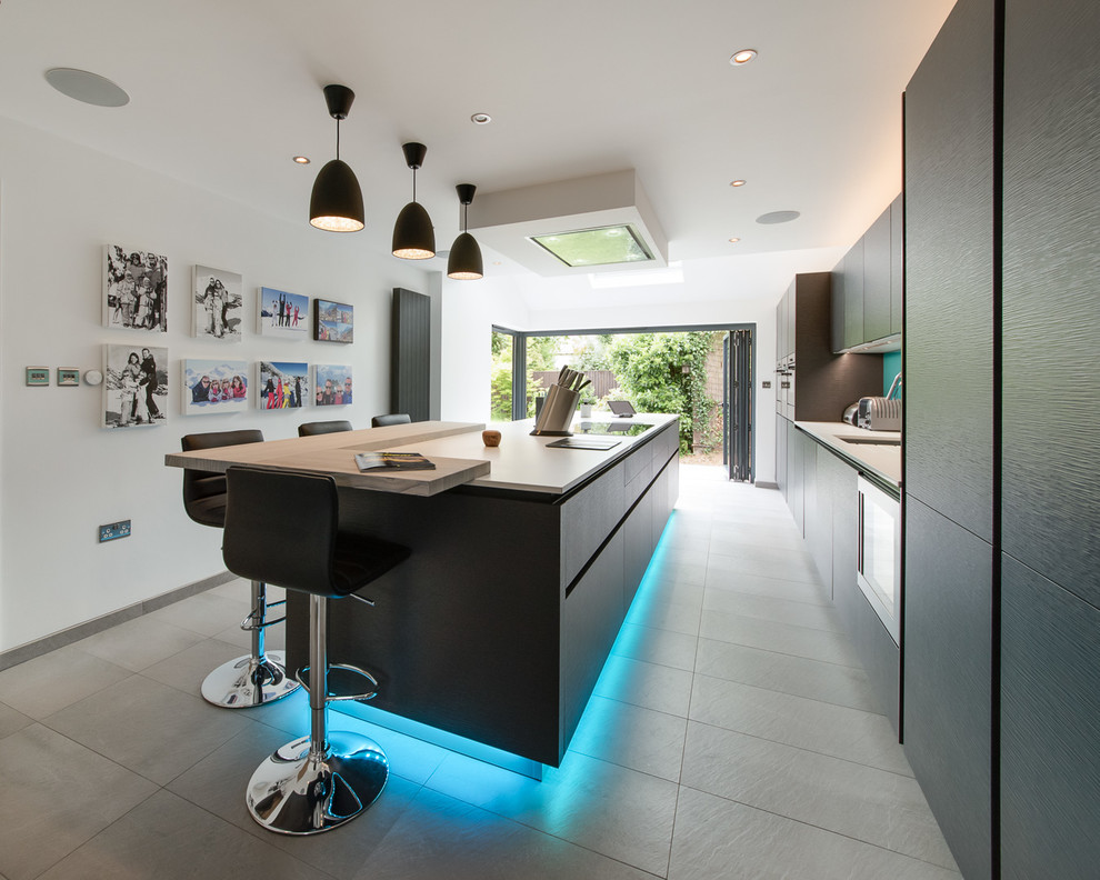 Design ideas for a large contemporary single-wall eat-in kitchen in Buckinghamshire with an undermount sink, flat-panel cabinets, black cabinets, quartz benchtops, blue splashback, glass sheet splashback, panelled appliances, ceramic floors, with island and grey floor.