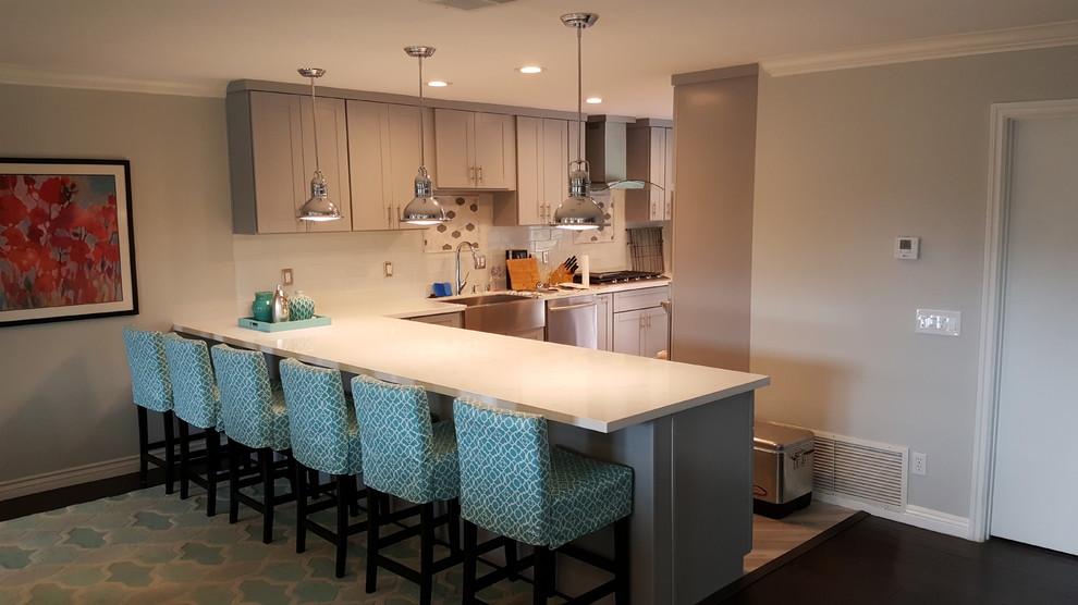 Mid-sized beach style open plan kitchen in San Diego with a farmhouse sink, shaker cabinets, grey cabinets, quartz benchtops, white splashback, subway tile splashback, stainless steel appliances, dark hardwood floors, a peninsula and brown floor.
