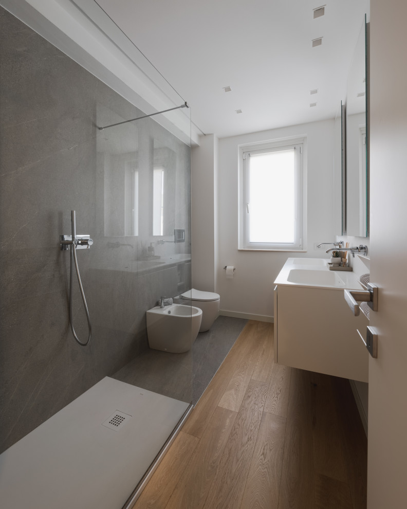 Inspiration for a medium sized contemporary shower room bathroom in Milan with flat-panel cabinets, white cabinets, a walk-in shower, a two-piece toilet, grey tiles, porcelain tiles, white walls, light hardwood flooring, a built-in sink, solid surface worktops, beige floors, white worktops, double sinks and a floating vanity unit.