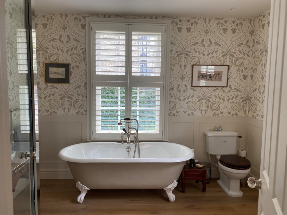 Modernes Badezimmer mit Löwenfuß-Badewanne, bodengleicher Dusche, bunten Wänden, braunem Holzboden und Tapetenwänden in London
