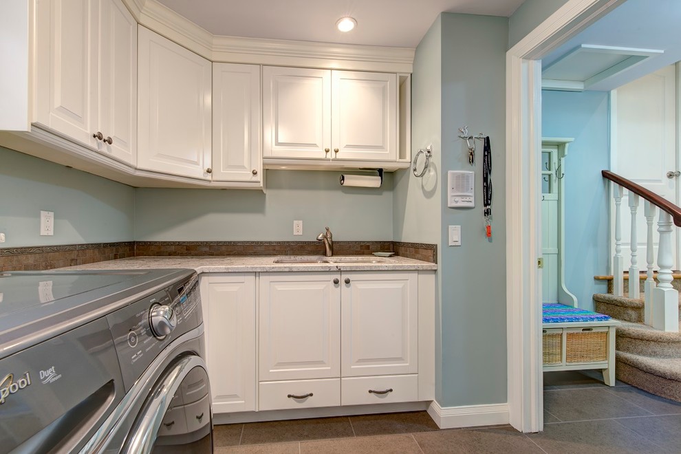 This is an example of a mid-sized traditional l-shaped utility room in Calgary with an undermount sink, raised-panel cabinets, white cabinets, granite benchtops, blue walls, ceramic floors and a side-by-side washer and dryer.