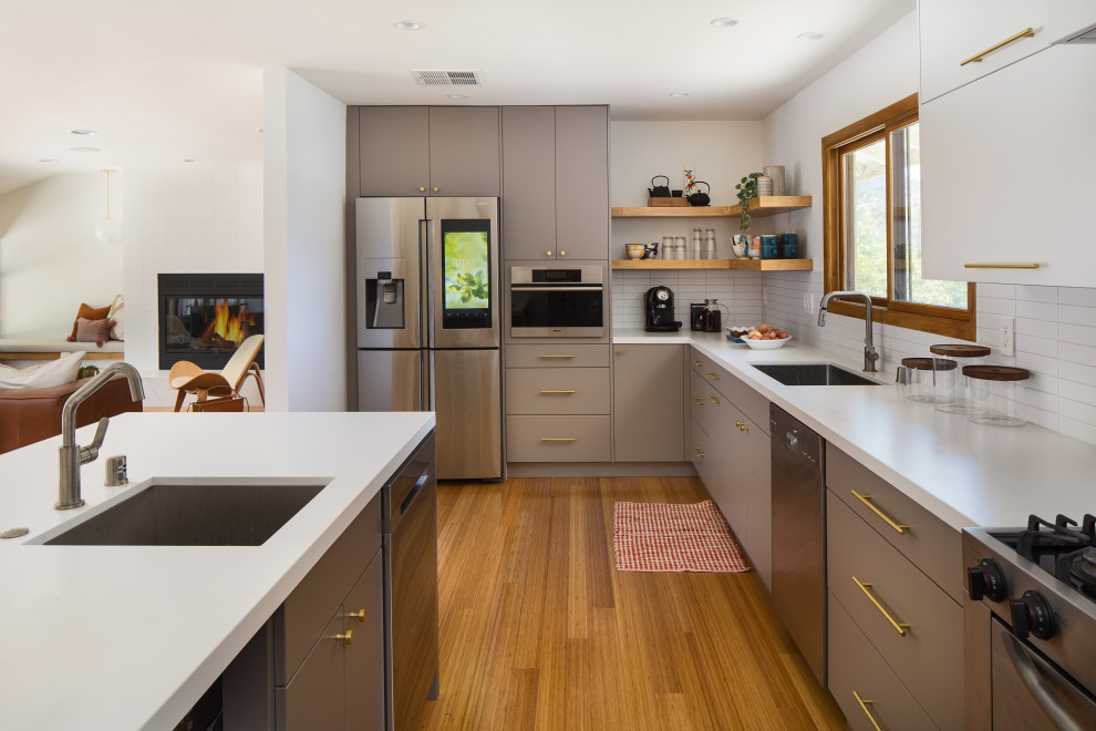 Design ideas for an expansive scandinavian galley eat-in kitchen in Los Angeles with an undermount sink, flat-panel cabinets, grey cabinets, quartz benchtops, white splashback, subway tile splashback, stainless steel appliances, bamboo floors, a peninsula, yellow floor and white benchtop.