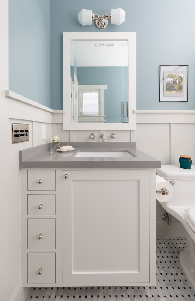 This is an example of a medium sized traditional ensuite bathroom in Los Angeles with shaker cabinets, white cabinets, a one-piece toilet, white walls, marble flooring, a submerged sink, engineered stone worktops, white floors, grey worktops, a single sink, a built in vanity unit and wainscoting.
