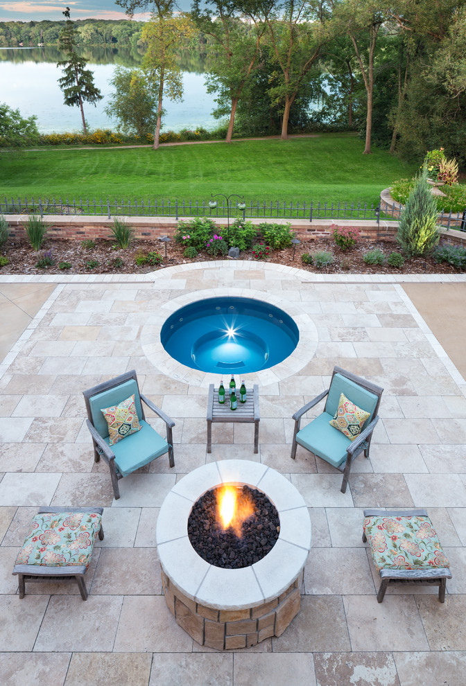Photo of a large traditional backyard patio in Minneapolis with a roof extension, a fire feature and natural stone pavers.