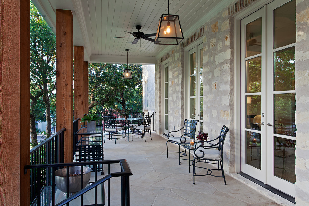 Photo of a large traditional front yard verandah in Austin with natural stone pavers and a roof extension.