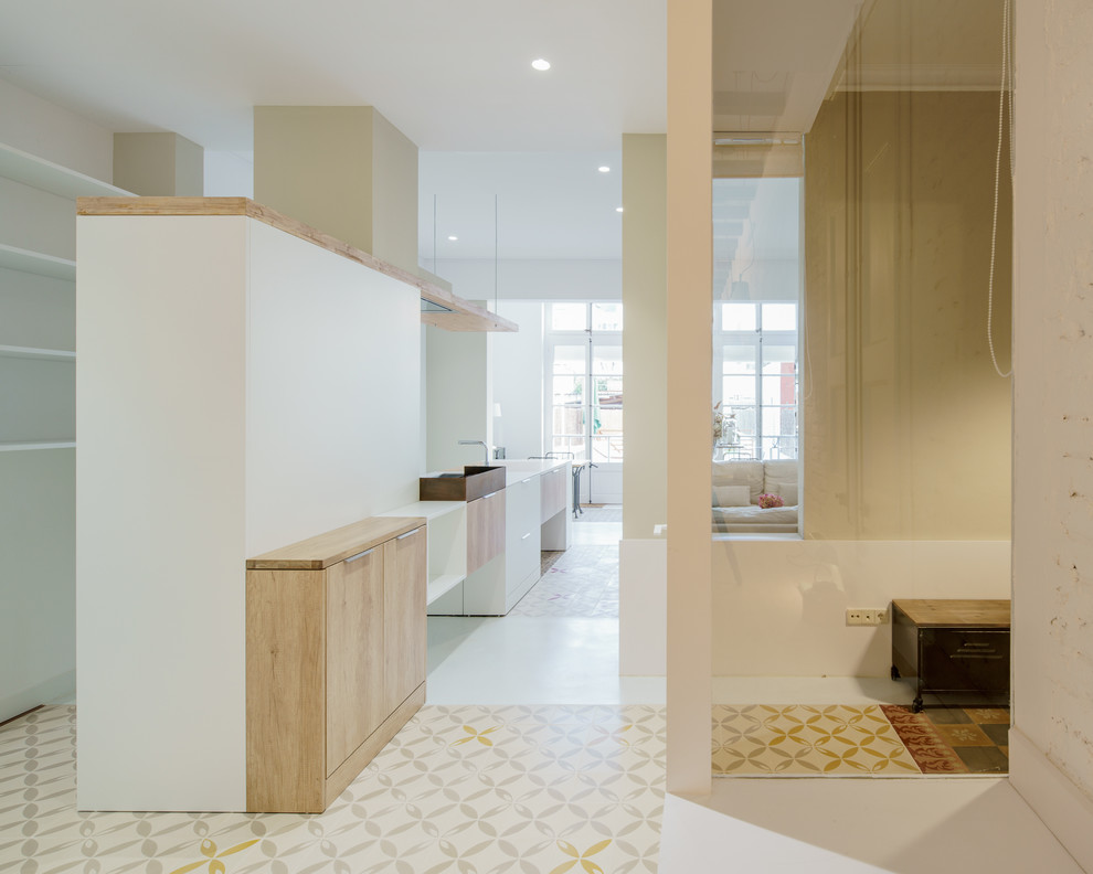 This is an example of a mid-sized modern single-wall open plan kitchen in Barcelona with flat-panel cabinets, white cabinets, quartz benchtops, concrete floors and a peninsula.