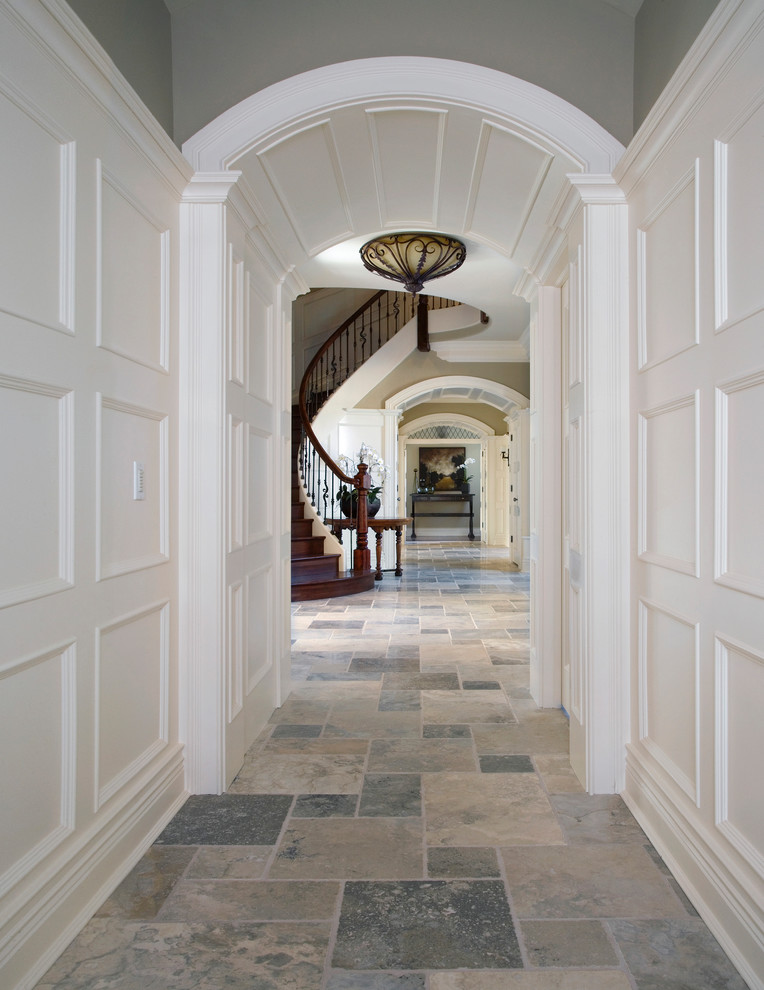 Photo of an expansive traditional hallway in Chicago with white walls, limestone floors and grey floor.