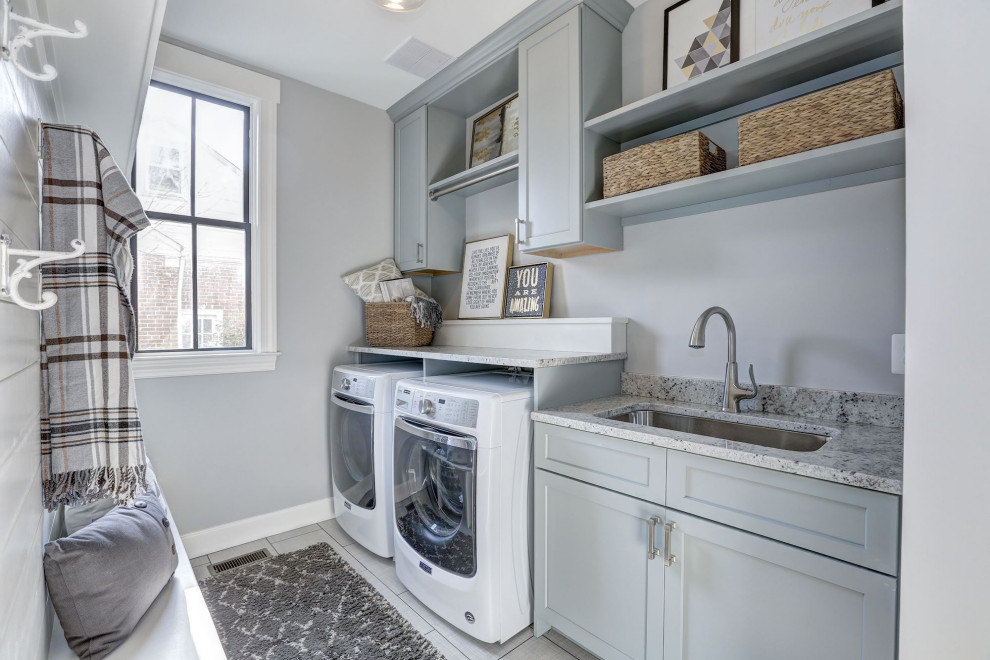 Inspiration for a small transitional single-wall dedicated laundry room in DC Metro with an undermount sink, flat-panel cabinets, green cabinets, granite benchtops, grey walls, a side-by-side washer and dryer, beige floor and multi-coloured benchtop.