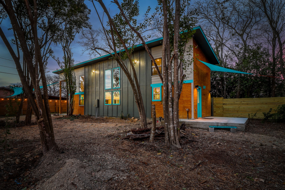Идея дизайна: маленький, двухэтажный, синий мини дом в стиле фьюжн с комбинированной облицовкой, односкатной крышей, металлической крышей, серой крышей и отделкой доской с нащельником для на участке и в саду