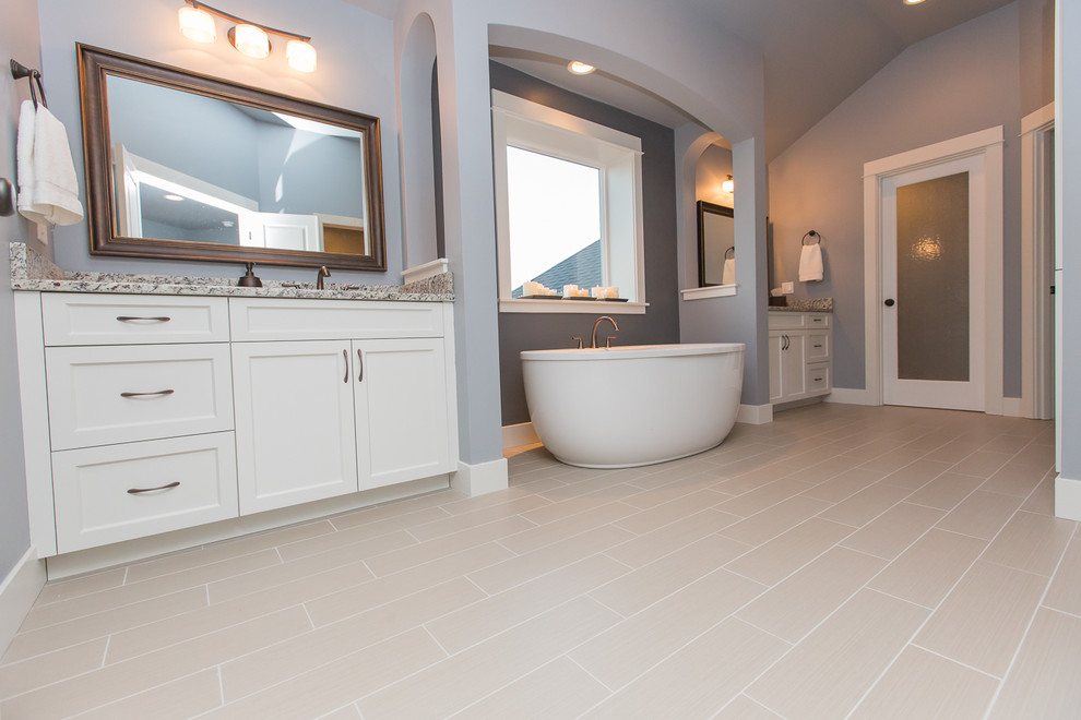 This is an example of a large traditional master bathroom in Portland with shaker cabinets, white cabinets, a freestanding tub, a double shower, a one-piece toilet, blue tile, ceramic tile, blue walls, ceramic floors and a drop-in sink.