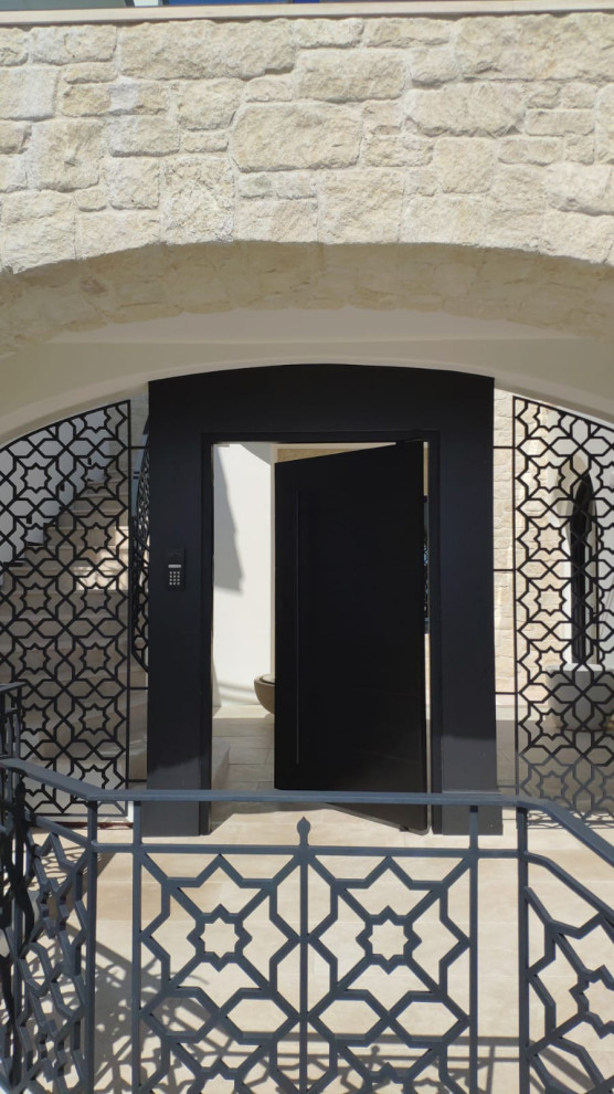 Immagine di una porta d'ingresso minimalista di medie dimensioni con pareti beige, una porta a pivot, una porta nera e pavimento beige