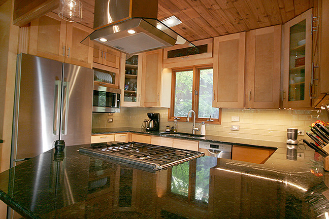 Example of a small transitional l-shaped porcelain tile eat-in kitchen design with shaker cabinets, light wood cabinets, granite countertops, beige backsplash, glass tile backsplash, stainless steel appliances and a peninsula