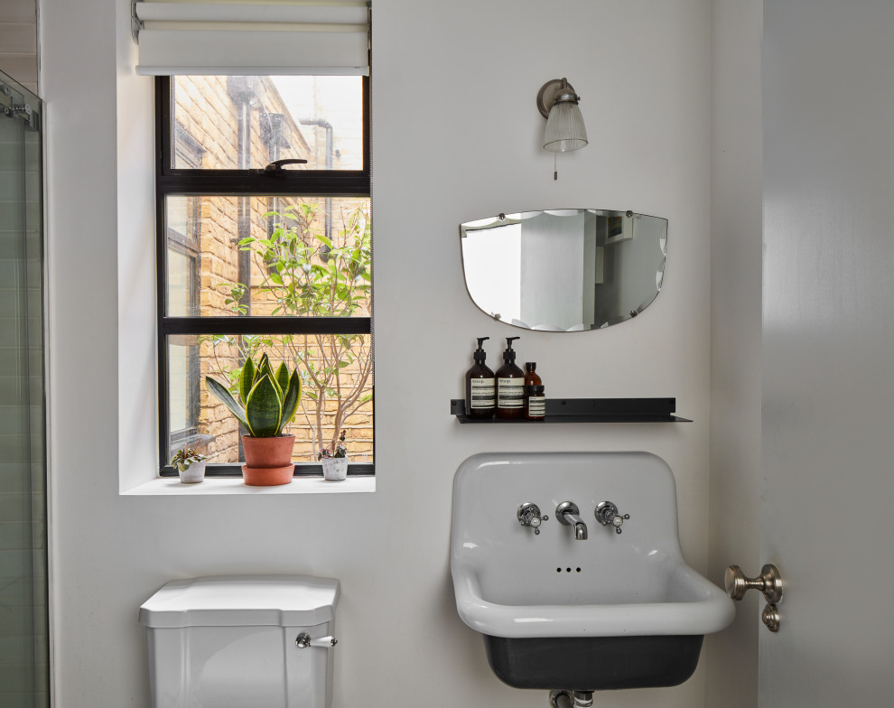 This is an example of a small industrial 3/4 bathroom in London with an open shower, a one-piece toilet, gray tile, ceramic tile, white walls, ceramic floors, a wall-mount sink, a sliding shower screen, a single vanity and a floating vanity.