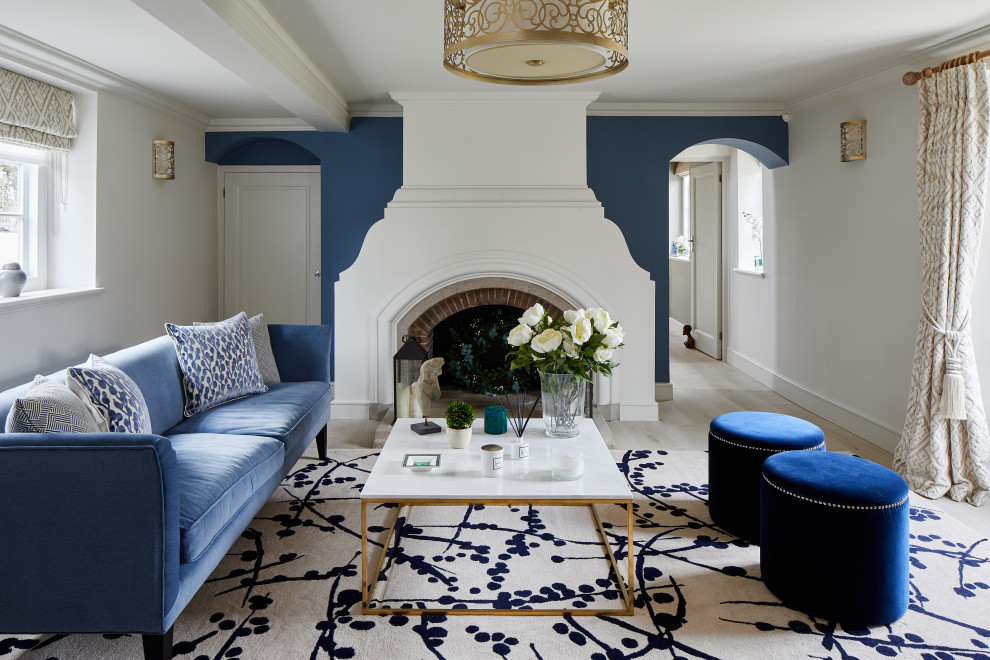На фото: гостиная комната среднего размера в классическом стиле с синими стенами, светлым паркетным полом, стандартным камином и фасадом камина из штукатурки с