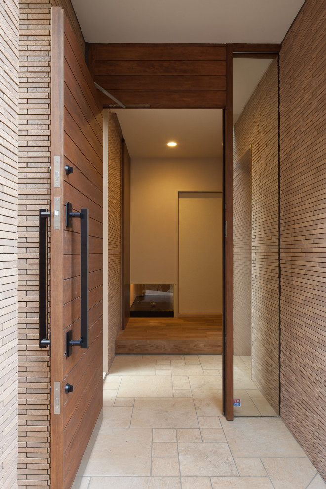Photo of a large modern front door in Tokyo with terra-cotta floors, a single front door, a medium wood front door, beige floor and brick walls.