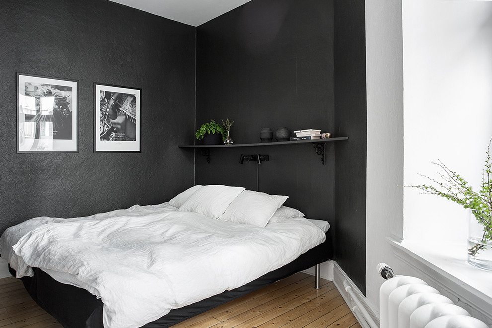 Design ideas for a mid-sized scandinavian master bedroom in Gothenburg with black walls, medium hardwood floors and no fireplace.