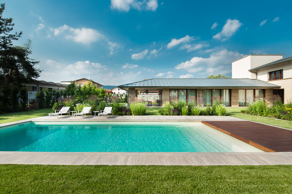 This is an example of a large contemporary rectangular pool in Milan with decking.