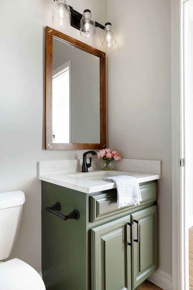 This is an example of a small traditional cloakroom in Minneapolis with raised-panel cabinets, green cabinets, a one-piece toilet, white tiles, white walls, vinyl flooring, a submerged sink, engineered stone worktops, beige floors, white worktops and a built in vanity unit.