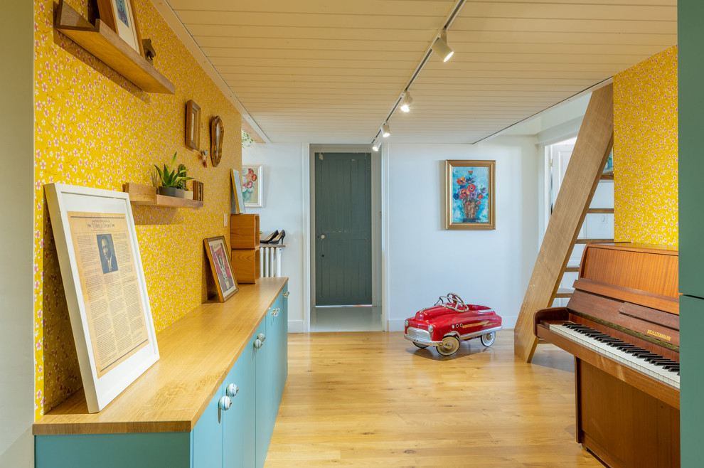 Foto de recibidores y pasillos retro de tamaño medio con paredes amarillas, suelo de madera clara y papel pintado
